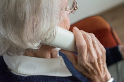 Eine ältere Frau hält einen Telefonhörer am Ohr
