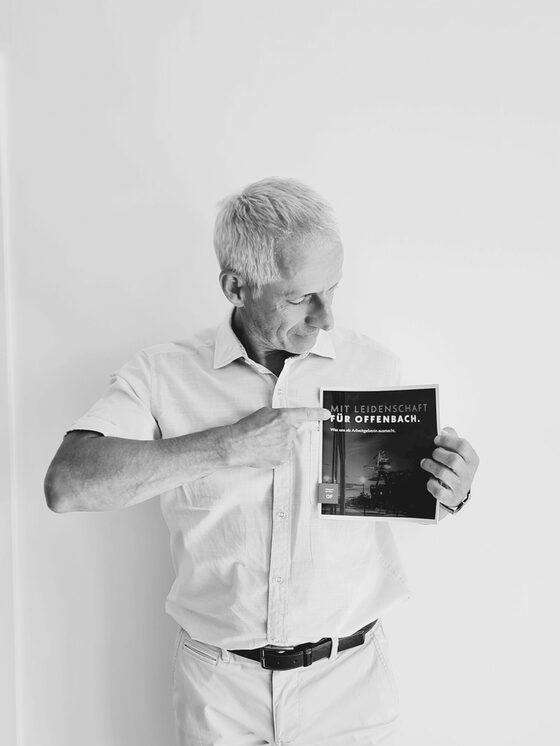 Thomas Heberer zeigt auf eine Textzeile einer Broschüre, die er in der Hand hält. Dort steht "Mit Leidenschaft für Offenbach".