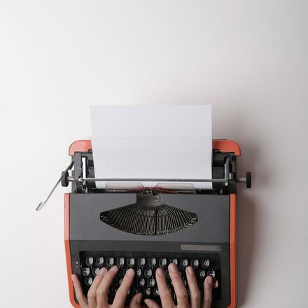 Zwei Hände tippen auf einer Schreibmaschine