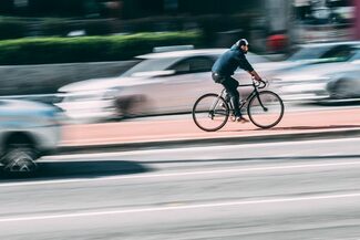 Symbolbild zu Mobilität: Radfahrer und fahrende Autos