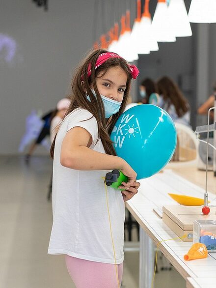 Ein Mädchen experimentiert mit einem Luftballon.
