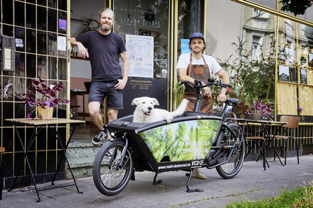 Betreiber von MyPiecycle mit E-Lastenrad und Hund vor dem Laden