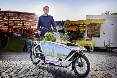 Mann mit E-Lastenrad auf dem Wochenmarkt am Wilhelmsplatz