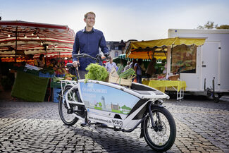 Mann mit E-Lastenrad auf dem Wochenmarkt am Wilhelmsplatz
