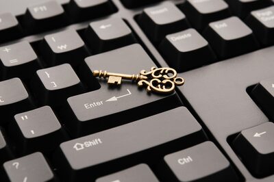 Goldener Schlüssel liegt auf einer schwarzen Tastatur.