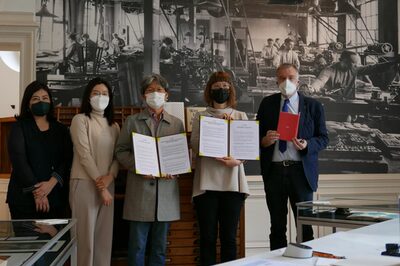 Gruppenfoto mit 6 Personen, zwei davon halten den unterzeichneten Kooperationsvertrag.