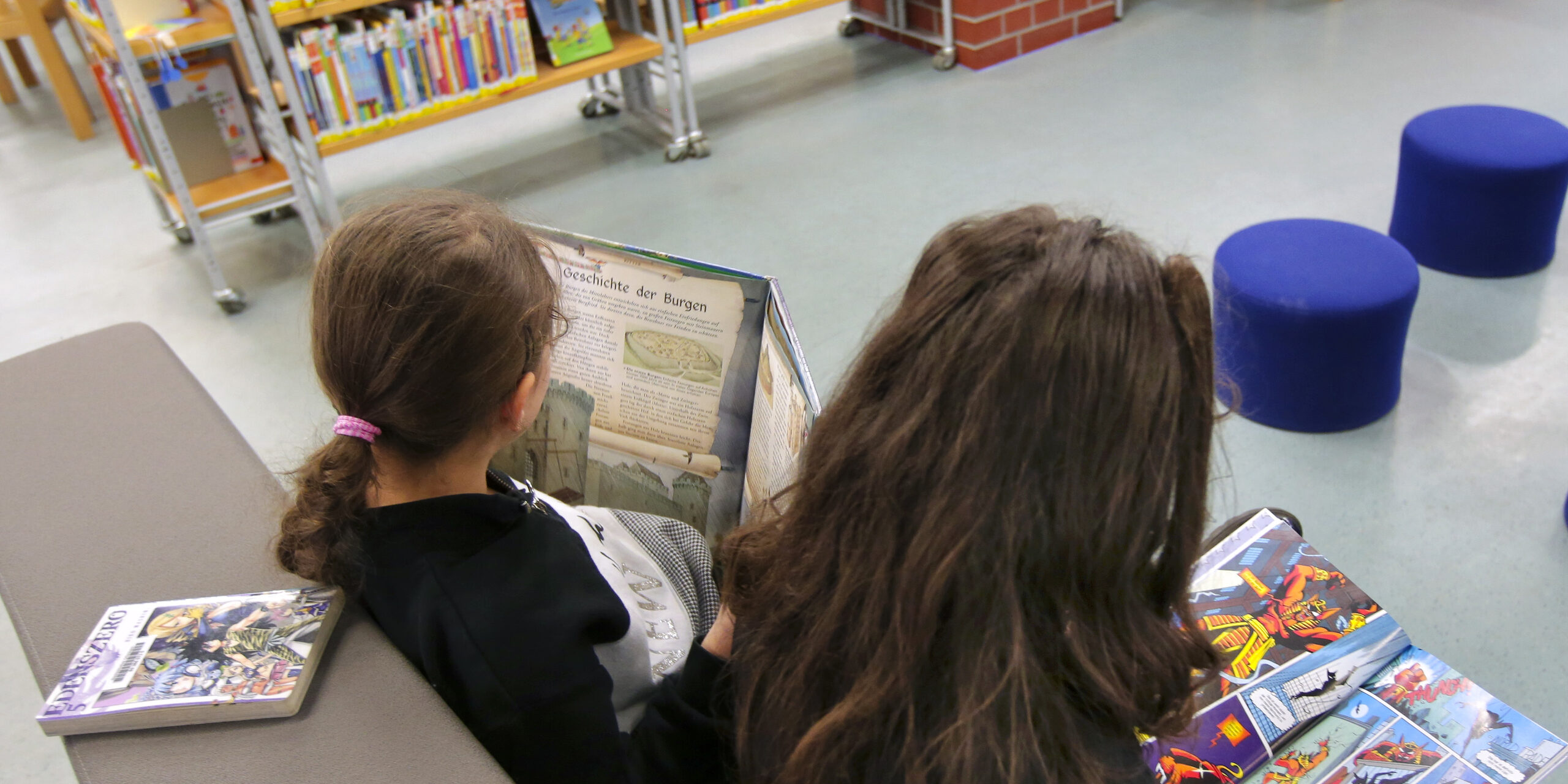 Kinder schauen sich Bücher in der Kinderbibliothek an.