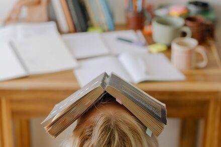 Mädchen mit Buch auf dem Kopf beim Lernen