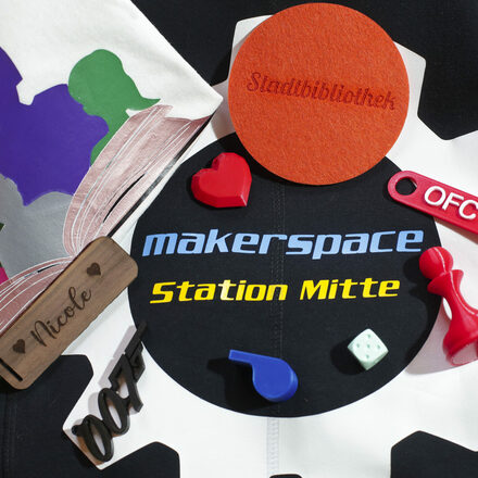 Gegenstände, die mit einem 3D-Drucker, einem Lasercutter und einem Schneidplotter hergestellt wurden, liegen auf einem Sweatshirt, auf dem Makerspace, Station Mitte steht.