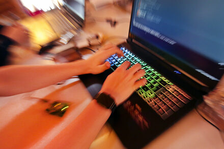 Jugendliche sitzen im Jugend hackt Lab an einem Tisch und programmieren mit Laptops.