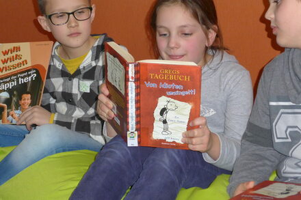 Drei Kinder mit Büchern beim Lesen.
