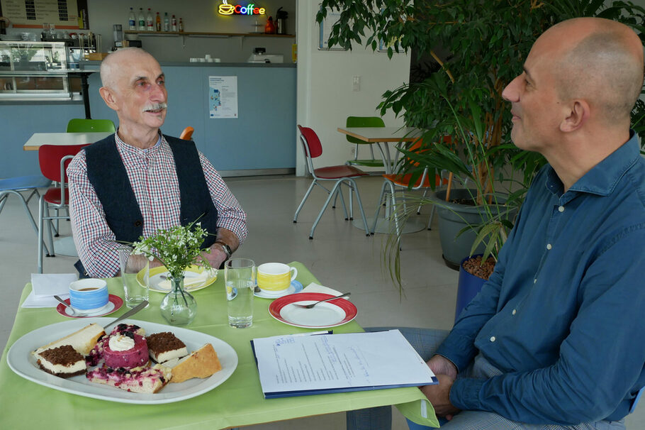 Rudi Schmitt und Dirk Wolk-Pöhlmann, am Tisch sitzend, im Gespräch