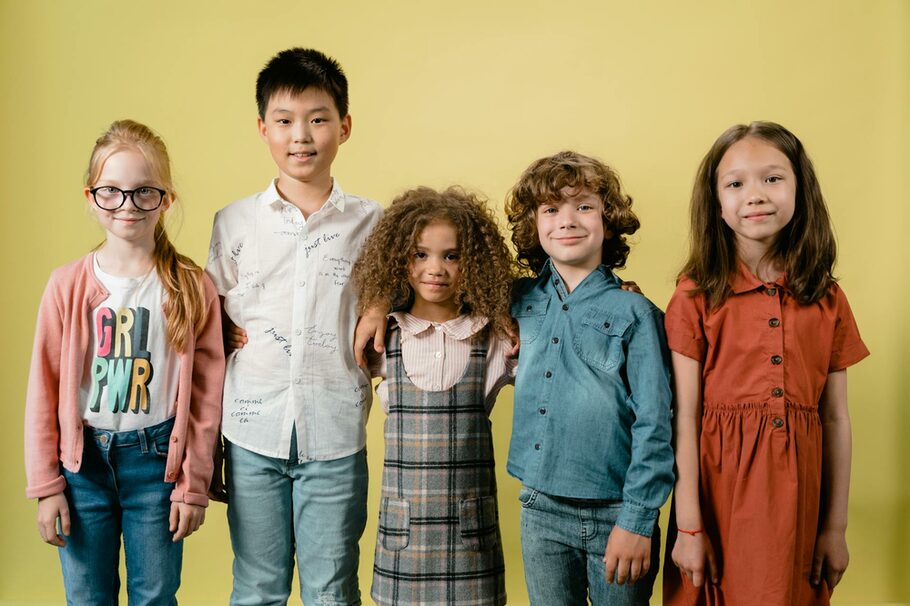 fünf Kinder stehen in einer Reihe vor einer grünen Wand