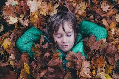 Junge liegt in Blätterhaufen