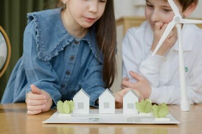 JUnge und Mädchen schaue auf ein Modell mit Häusern und einem Windkraftrad