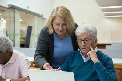 Frau zeigt einem Mann etwas auf einem Bildschirm eines Laptops