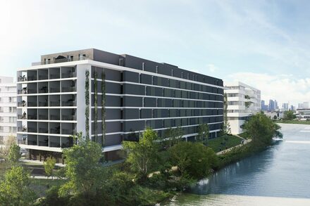 Modell des neuen Aparthotels, das derzeit gebaut wird. Das Gebäude ist modern, rechteckig und in Grautönen gestaltet.