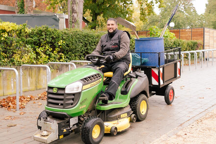Sinan Altindag fährt mit einem kleinen Traktor über das Außengelände der Edith-Stein-Schule.