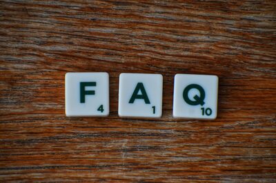 Drei Buchstabenblättchen auf einem Tisch bilden das Wort FAQ.