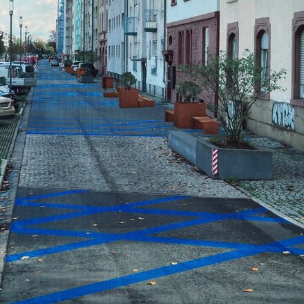 Streifenförmig-blaue Bodenmarkierungen auf einer Anliegerstraße.