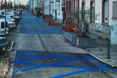 Siegerentwurf mit blauen Markierungen auf der Straße und Pflanzenkübeln am Rand.