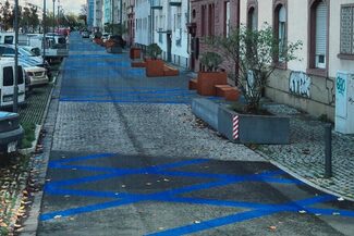 Siegerentwurf mit blauen Markierungen auf der Straße und Pflanzenkübeln am Rand.