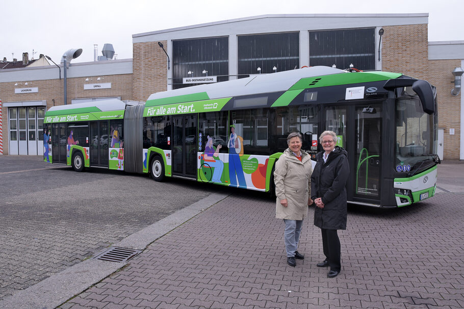 Anja Georgi und Sabine Groß stehen vor dem neu beklebten Bus.