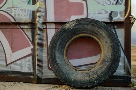 Alter Reifen lehnt an einer Wand mit Grafitty