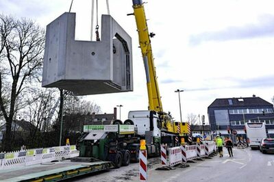 Ein rund 50 Tonnen schwerer Schacht aus beton wird in der Kanalbaugrube auf der Mühlheimer Straße versenkt.