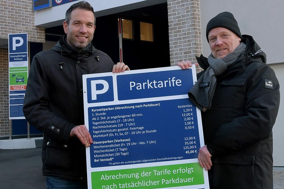 Martin Wilhelm und Frank Herzog stehen von dem Innenstadt-Parkhaus und halten die Preistafel in den Händen.