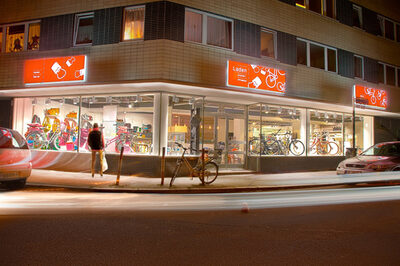 Abendlich beleuchteter Fahrradladen von außen